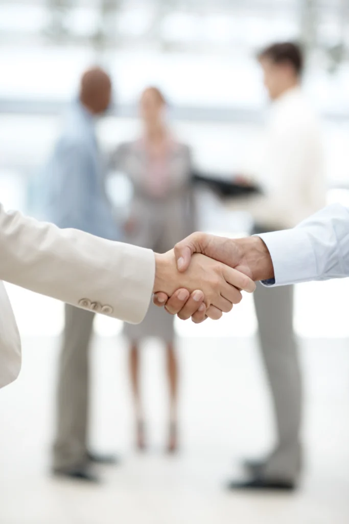 Business professionals shaking hands in an office, symbolizing partnership and collaboration in HR consultancy in Ernakulam.
