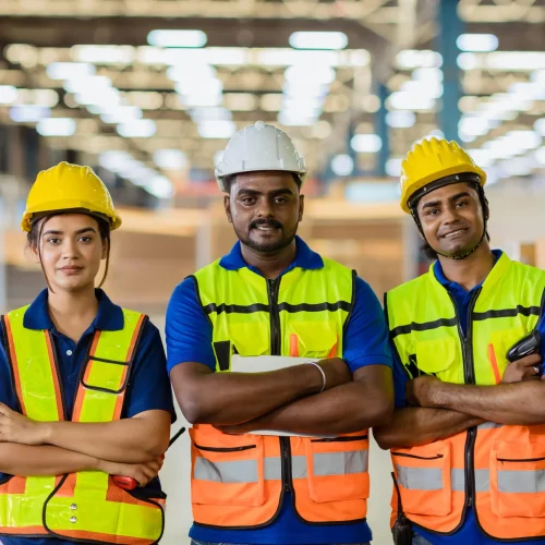Three workers stand in a warehouse surrounded by stacked boxes, engaged in organizing the inventory.